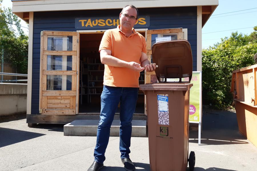 KSJ-Werkleiter Uwe Feige wirft Korken in einen Sammelbehälter. 