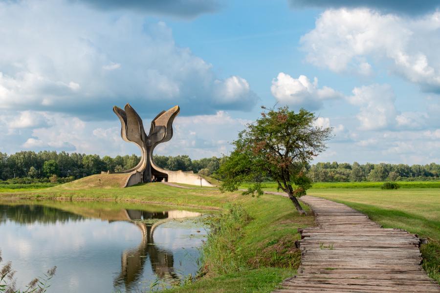 Eine Landschaft mit einem Denkmal, welches sich in den Himmel öffnet