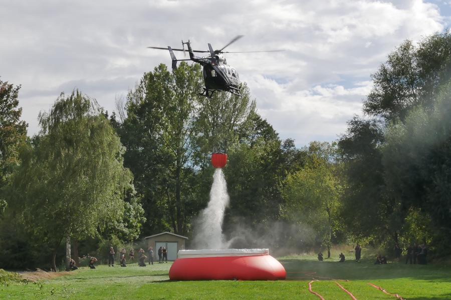 Ein Hubschrauber entlädt sehr viel Wasser in einen Behälter