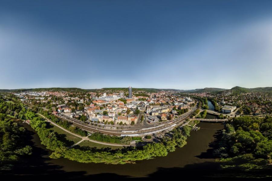 Panoramaaufnahme der Stadt Jena mit viel Grün, einem Fluss und vielen Gebäuden