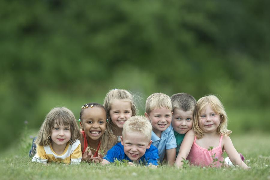 Eine Gruppe von Kindern liegt auf einer Wiese.