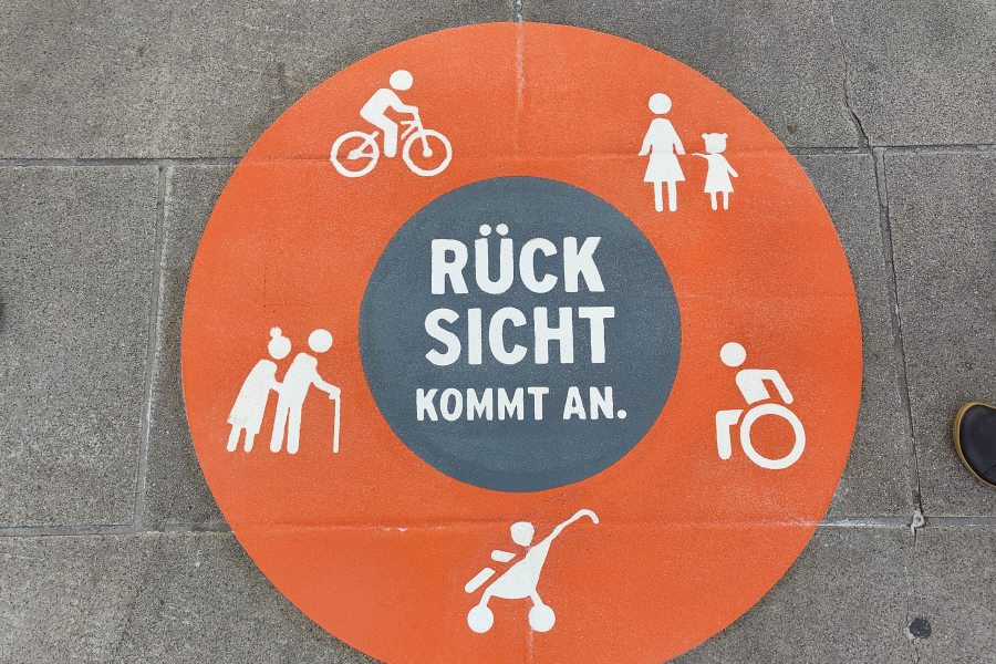 Bordenmarkierung: Orangerkreis mit weißen Symbolen (Rollstuhlfahrer, Senioren, Mutter mit Kind, KInderwagen, Radfahrer) in der Mitte steht "Rücksicht kommt an"