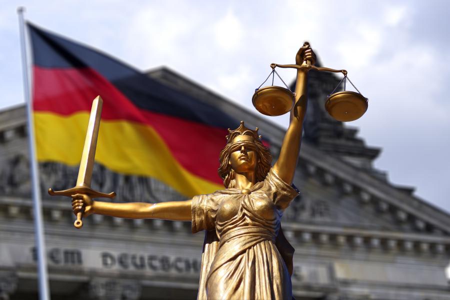 Eine Figur, die Jura symbolisiert vor der deutschen Flagge