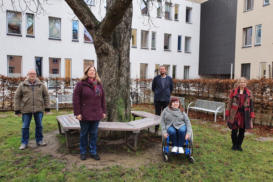 Auf dem Foto stehen im Freien mit Abstand nebeneinander 5 Personen: zwie Männer und drei Frauen