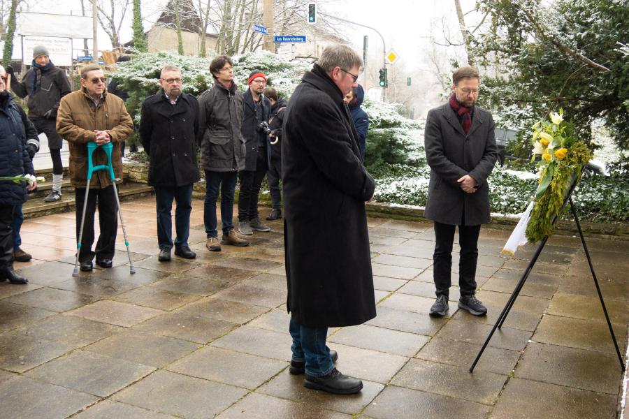 Menschen verharren vor einem Kranz