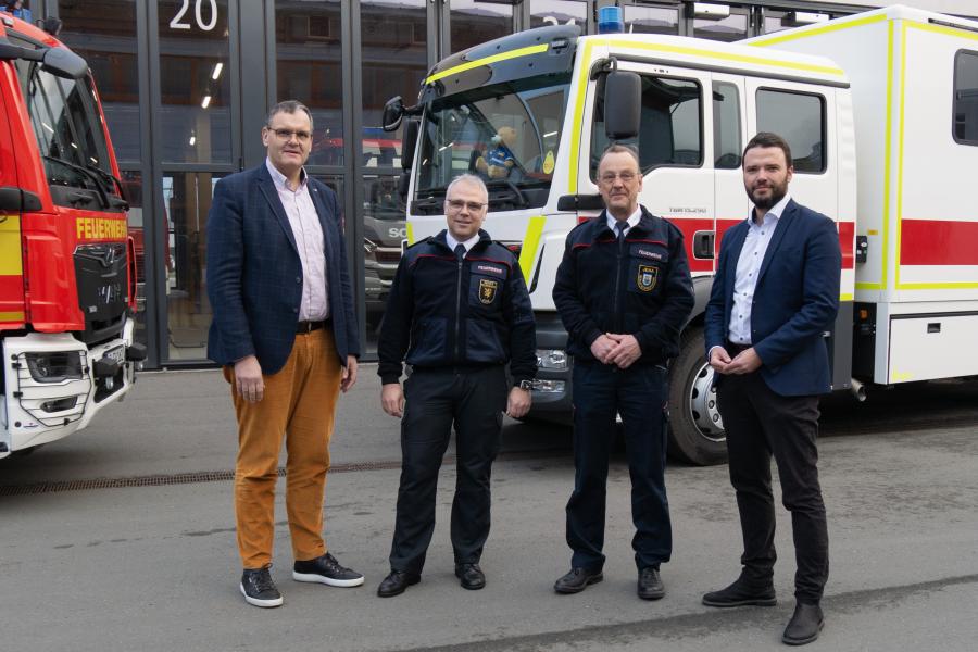 Vier Männer vor zwei Fueerwerfahrzeugen