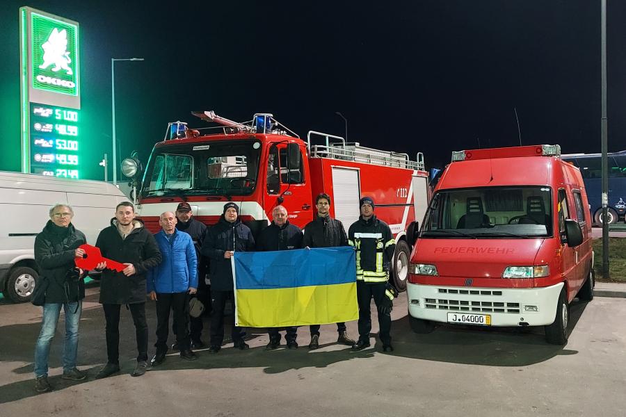 Menschen stehen vor mehreren Feuerwehrfahrzeuge