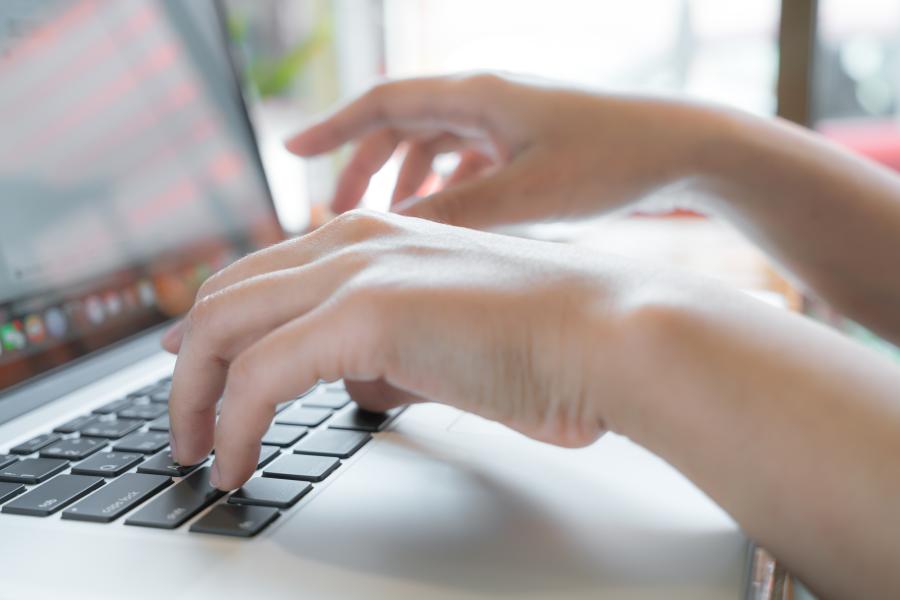 Nahaufnahme eines Laptops. Hände tippen auf der Tastatur.