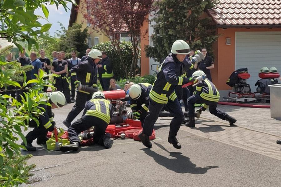 Feuerwehrmänner rennen mit Schläuchen in der Hand
