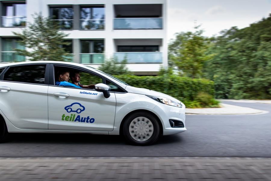 Ein Auto des Carsharing-Anbieters teilAuto fährt durch ein Wohngebiet