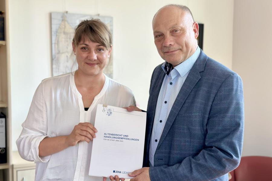 Eine Frau und ein Mann halten ein Dokument in die Kamera