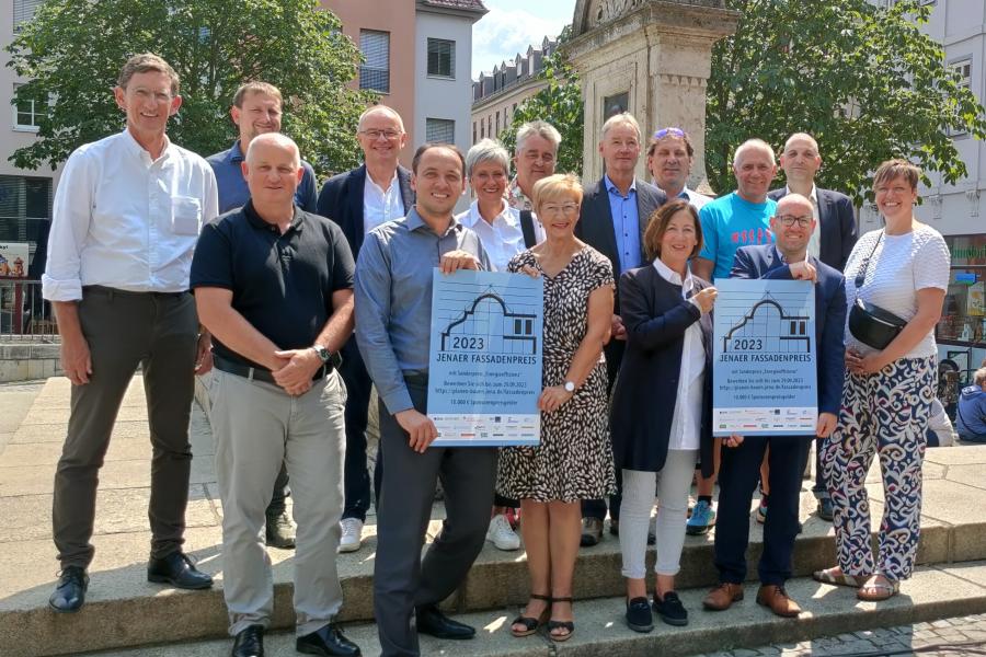 Bürgermeister Christian Gerlitz mit Sponsor*innen des Fassadenpreises stehen am Brunnen auf dem Marktplatz..