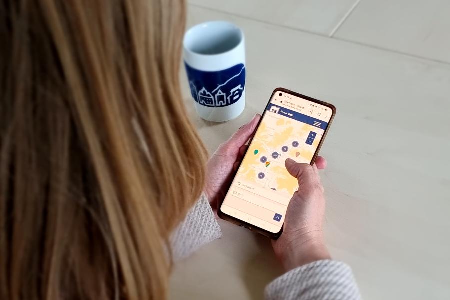 Eine Frau schaut sich am Smartphone die Wandelkarte Jena an.