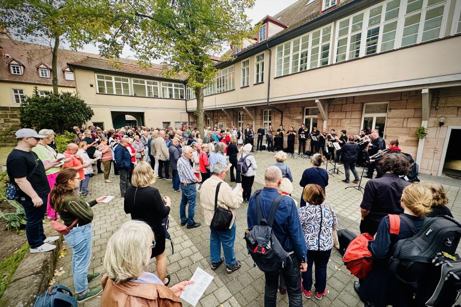Menschen stehen in einem Innenhof und singen