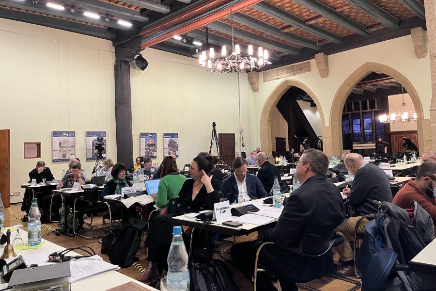 Im Rathaus-Plenarsaal sitzen Stadtratsmitglieder an Tischen