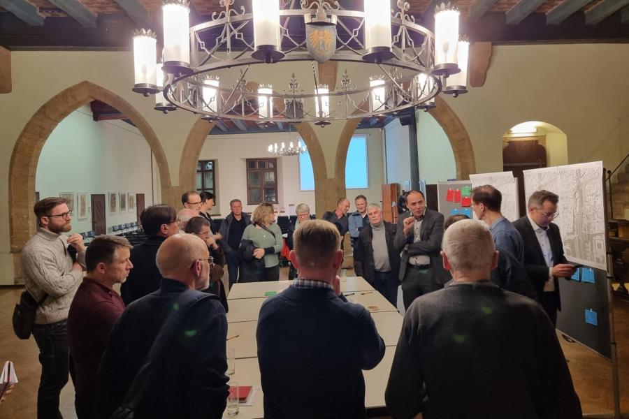 Viele Personen stehen um einen großen Tisch mit Planungsunterlagen.