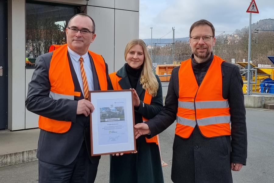 Andrea Kostrowski, Referentin Kreislaufwirtschaft DUH, überreicht KSJ- Werkleiter Uwe Feige (l.) und OB Thomas Nitzsche die Urkunde. 
