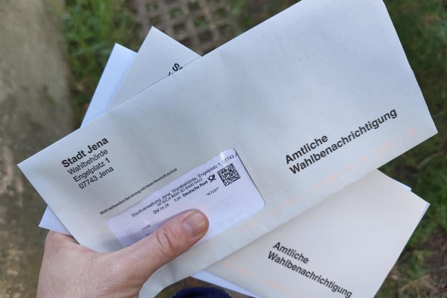 Eine Hand hält zwei briefumschläge mit dem Titel Amtliche Wahlbenachrichtigung
