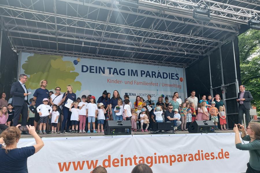 Kinder, Jugendliche und Erwachsene stehen auf einer Bühne und bekommen Urkunden überreicht