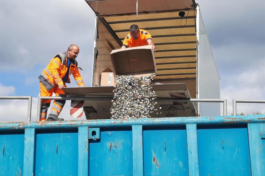 KSJ-Mitarbeiter schütten die abgeholten Kronkorken in einen Container.