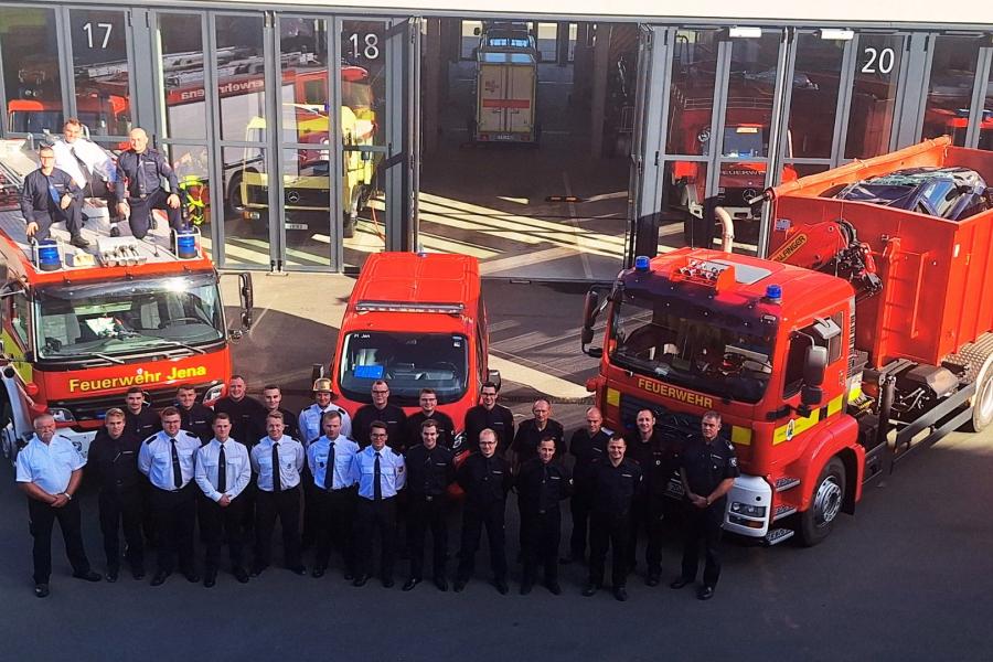 Gruppe von Feuerwehrmännern steht vor drei Feuerwehren.