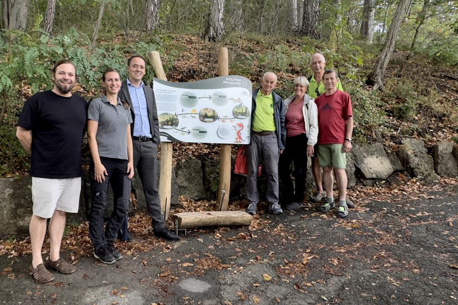Menschen vor einer Informationstafel im Wald