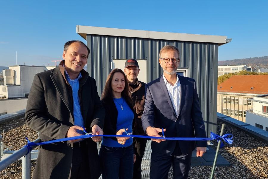 Bürgermeister Christian Gerlitz (v.l.), Kerstin Wuthenow (Ehrenamtliche Stadttaubenhilfe) und  Detlef Graba (Director Asset Management Technik und Nachhaltigkeit Real I.S. AG) schneiden ein Band vor dem neuen Taubenhaus durch. Hinter ihnen steht Taubenwart Torsten Schulz.