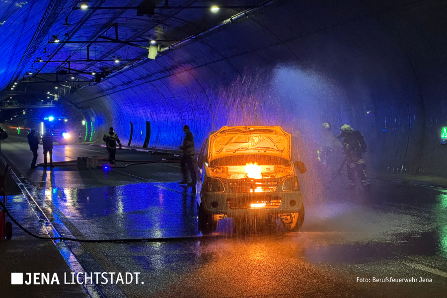 Ein Auto brennt im Tunnel. Feuerwehrleute löschen es.