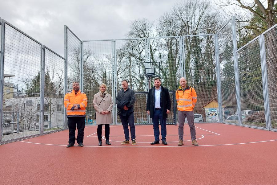 Fünf Personen stehen auf einem Bolzplatz.