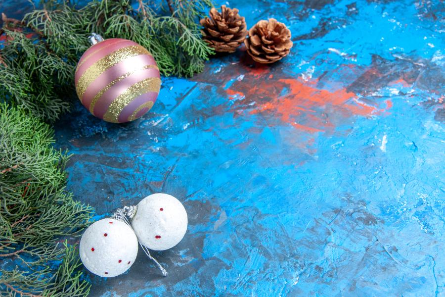 Tannenzapfen, Tannengrün, Weihnachtsbaumkugel auf blauem Geschenkpapier