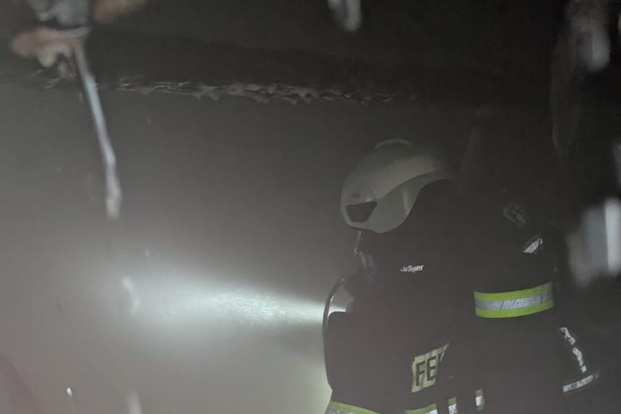 Ein Feuerwehrmann in Vollausrüstung geht durch einen verrauchten Keller.