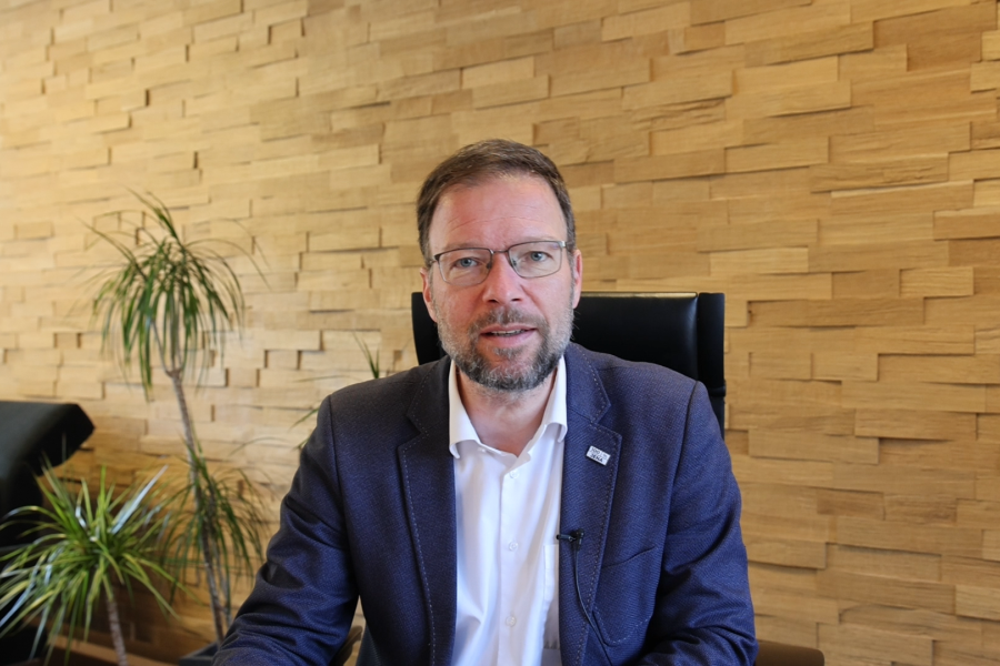 Oberbürgermeister Thomas Nitzsche sitzt an einem Tisch in seinem Büro und schaut in die Kamera.