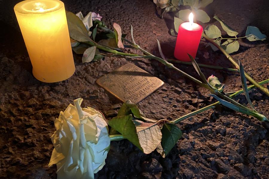 Blumen und Kerzen neben einem Stolperstein