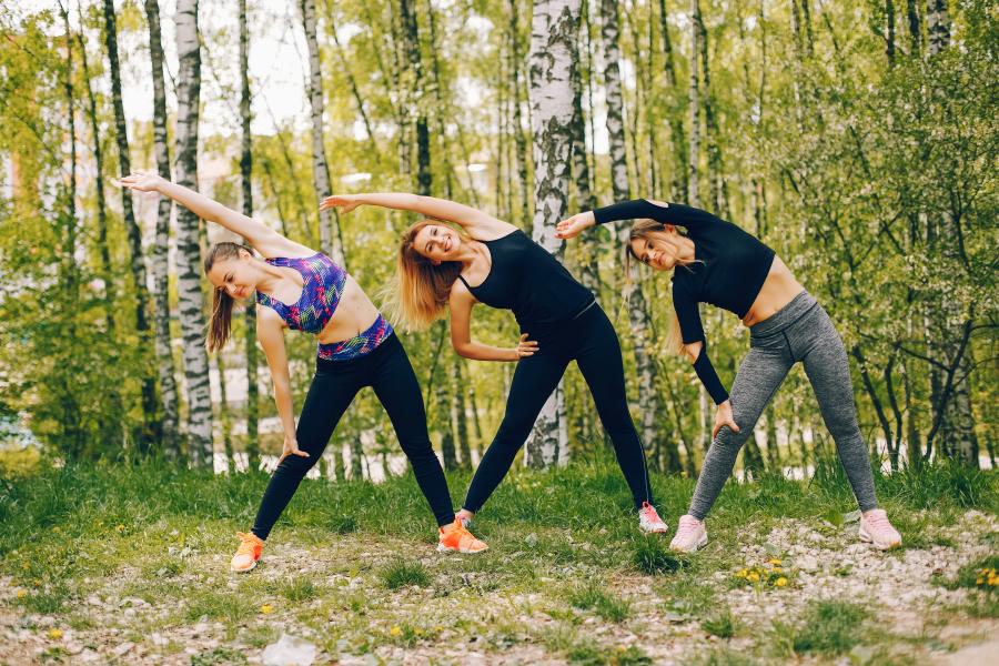 Drei Frauen machen draußen Gymnastik.