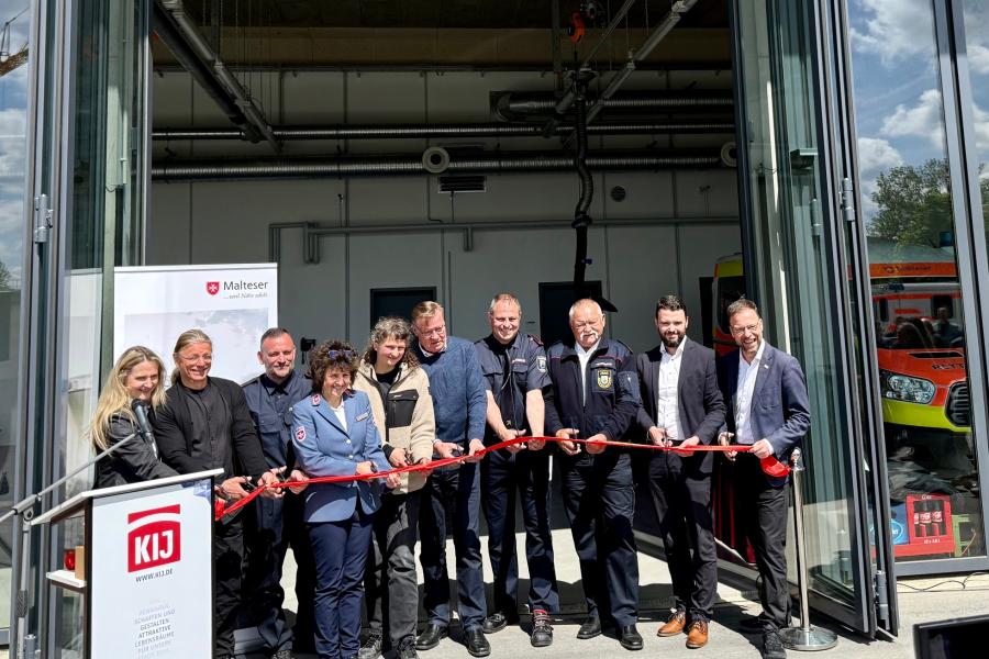 Eine Gruppe aus Männern und Frauen zerschneidet rotes Band.
