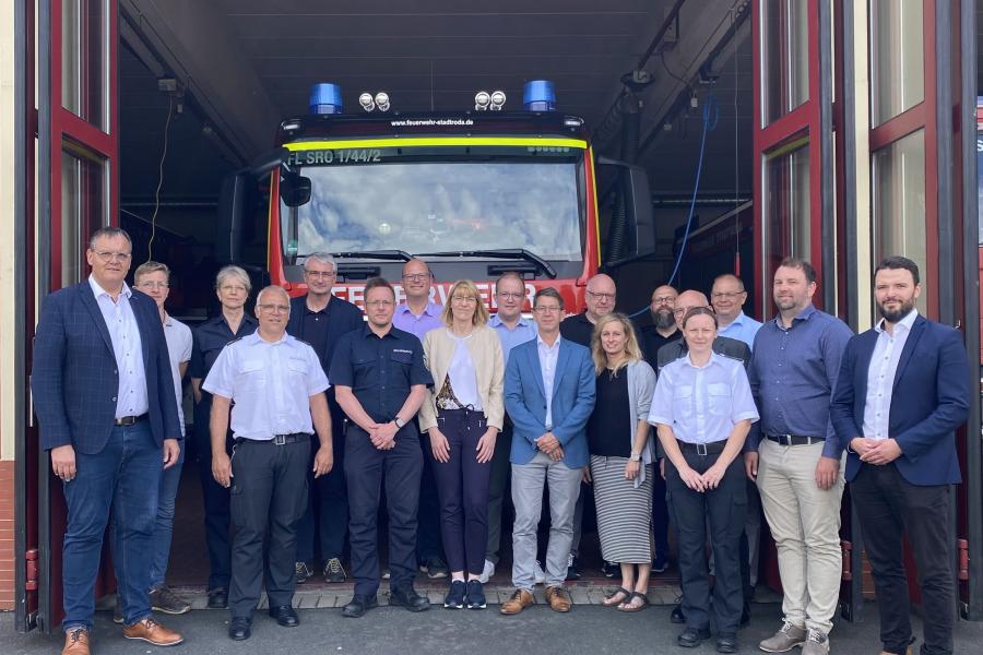 Viele Menschen stehen vor einer Feuerwache und schauen in die Kamera.