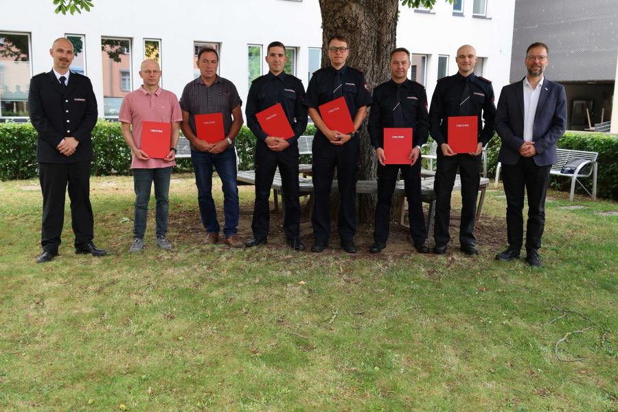 Feuerwehrmänner und OB schauen in die Kamera.