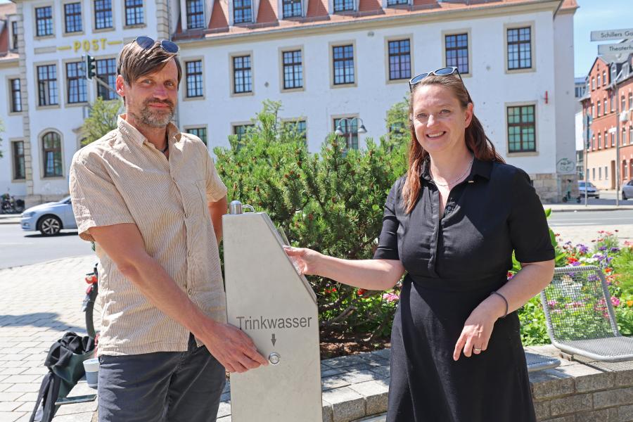 Zwei Personen an einem Trinkwasserbrunnen