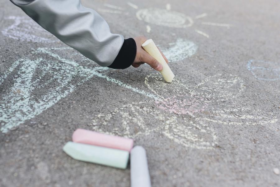 Kind, das mit Kreide auf die Straße zeichnet