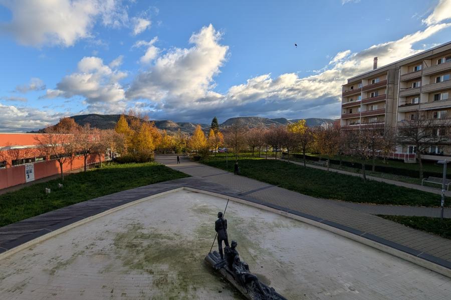 Blick auf einen Brunnen mit umliegenden Gebäuden.
