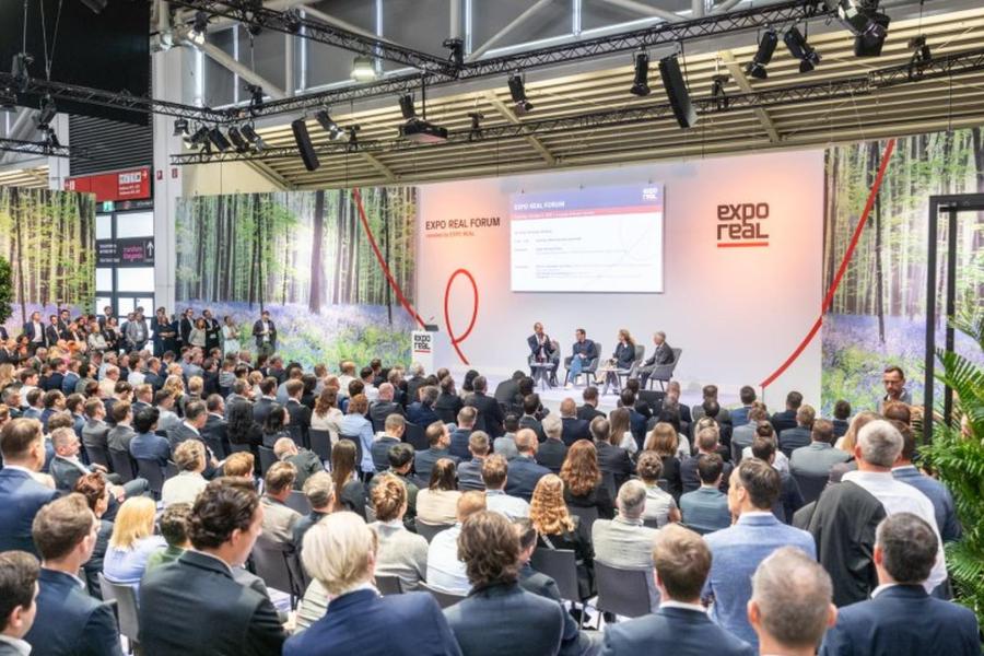 Viele Menschen sitzen im Publikum und hören Podiumsdiskussion zu.