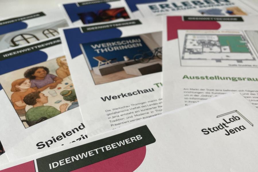 Auf einem Tisch liegen mehrere Broschüren zum Ideenwettbewerb 2025