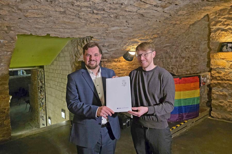 Zwei Personen halten ein Dokument in der Hand. 