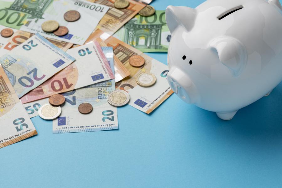 Bargeld liegt auf einer Fläche verteilt. Daneben steht ein Sparschwein.