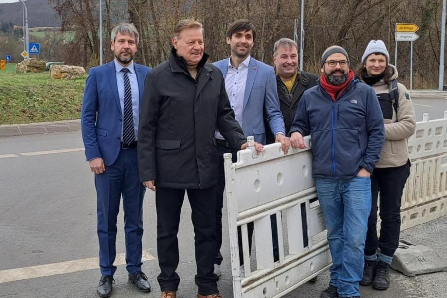Sechs Personen stehen an einer geöffneten Absperrung.