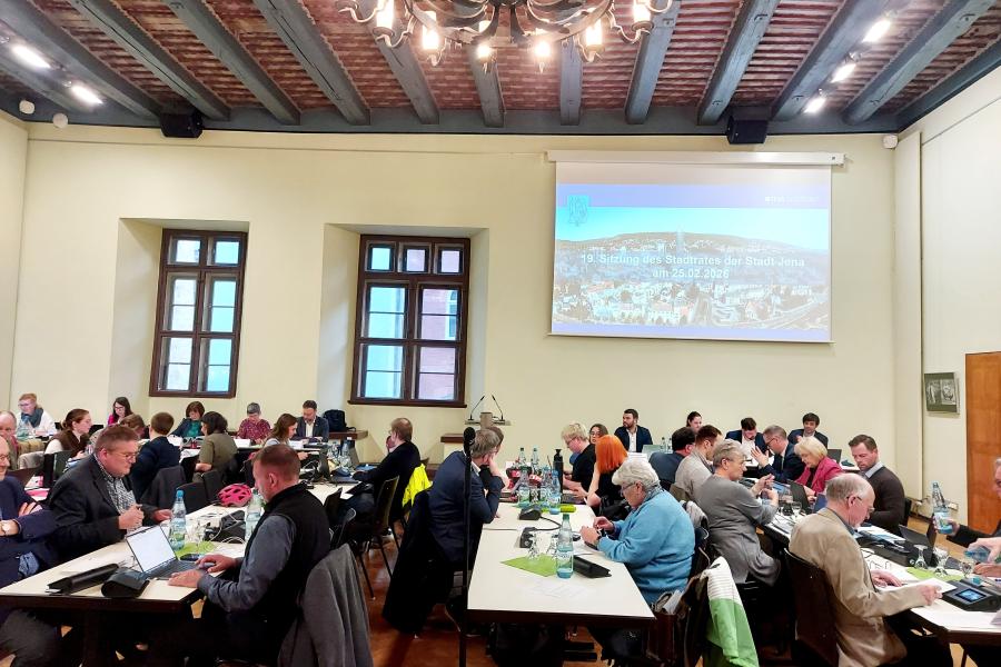 Stadtratsmitglieder sitzen an Tischen im Historischen Rathaus während der Stadtratssitzung