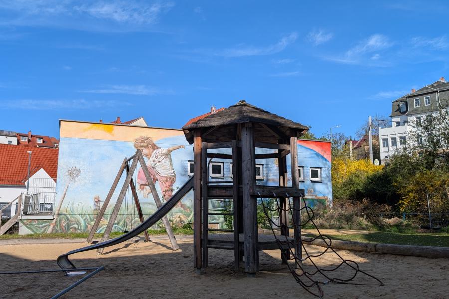 Blick auf einen kleinen Spielplatz mit Rutsche, Schaukel und Kletterturm