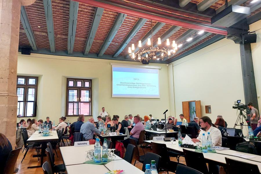 Stadtratsmitglieder sitzen an Tischen im Historischen Rathauses während der Stadtratssitzung