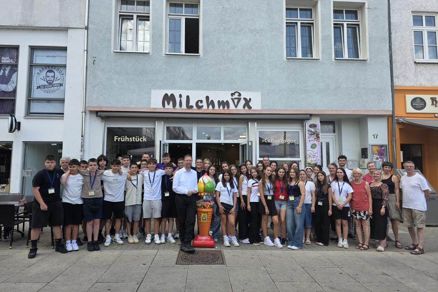 Kinder und Erwachsene stehen vor dem Eiscafé Milchmix als Gruppe zusammen