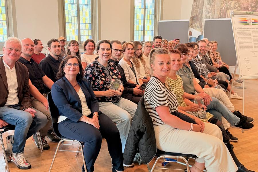 Viele Menschen in einem Raum und alle schauen in die Kamera